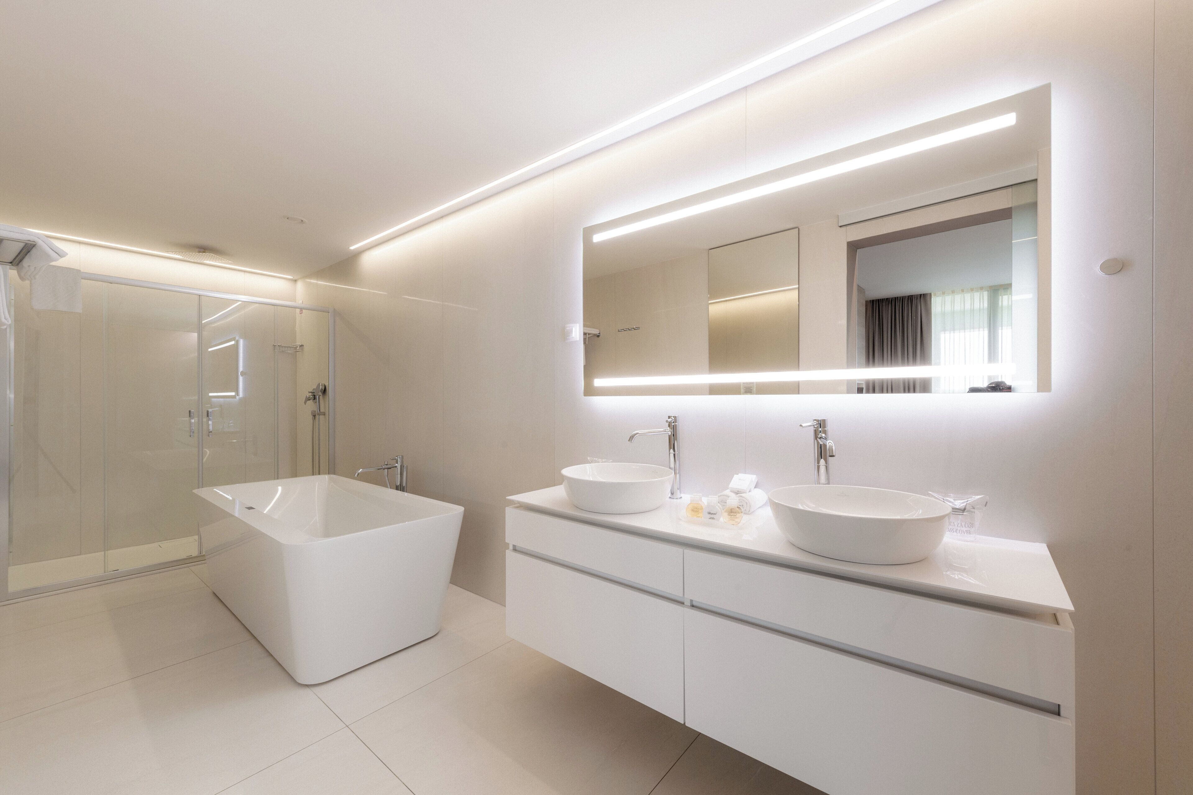 Un baño moderno con una bañera grande, dos lavamanos y una ducha a ras de suelo.