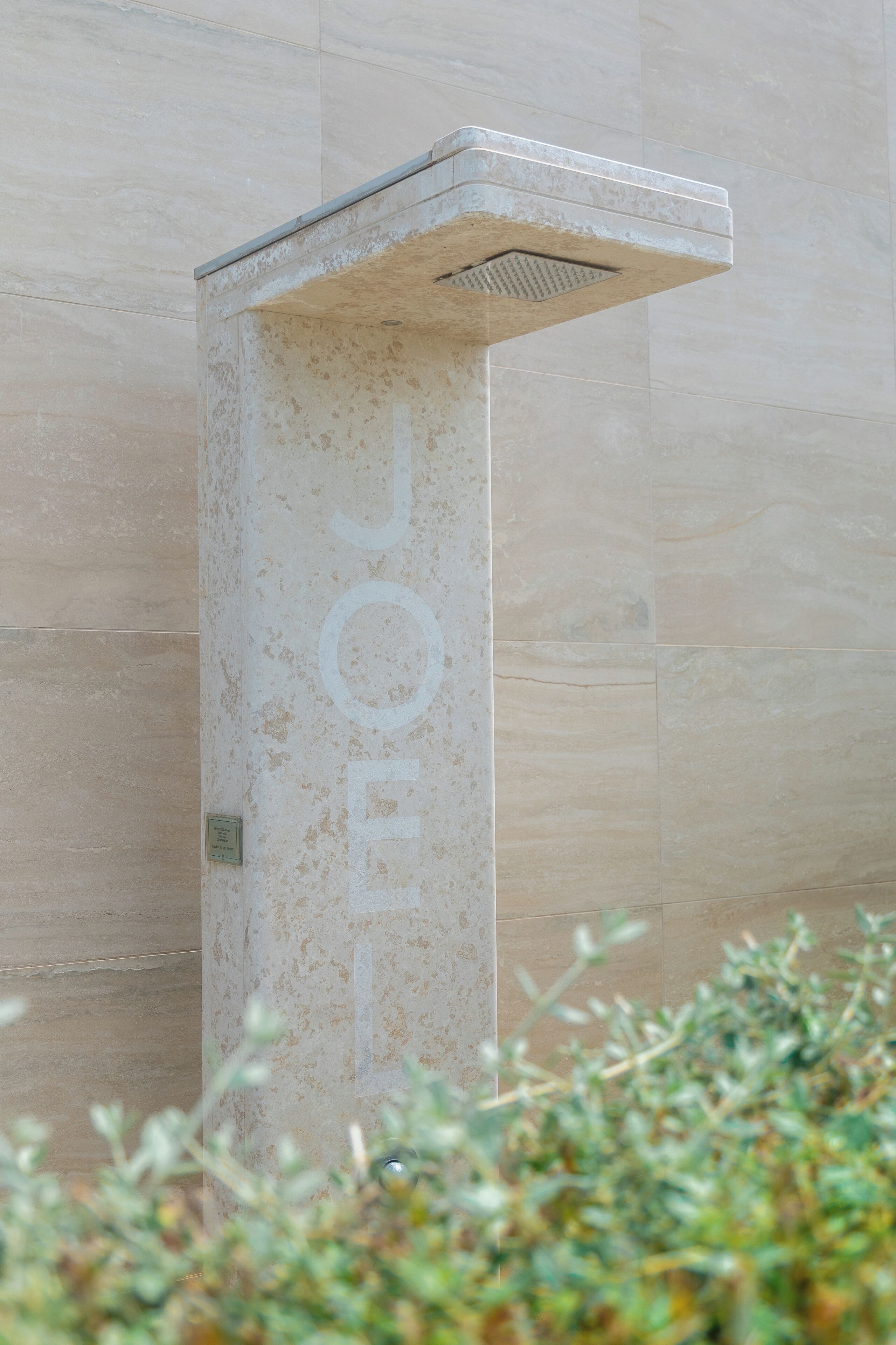 A stone pillar with the word 'JOEL' engraved on it, set against a tiled wall.