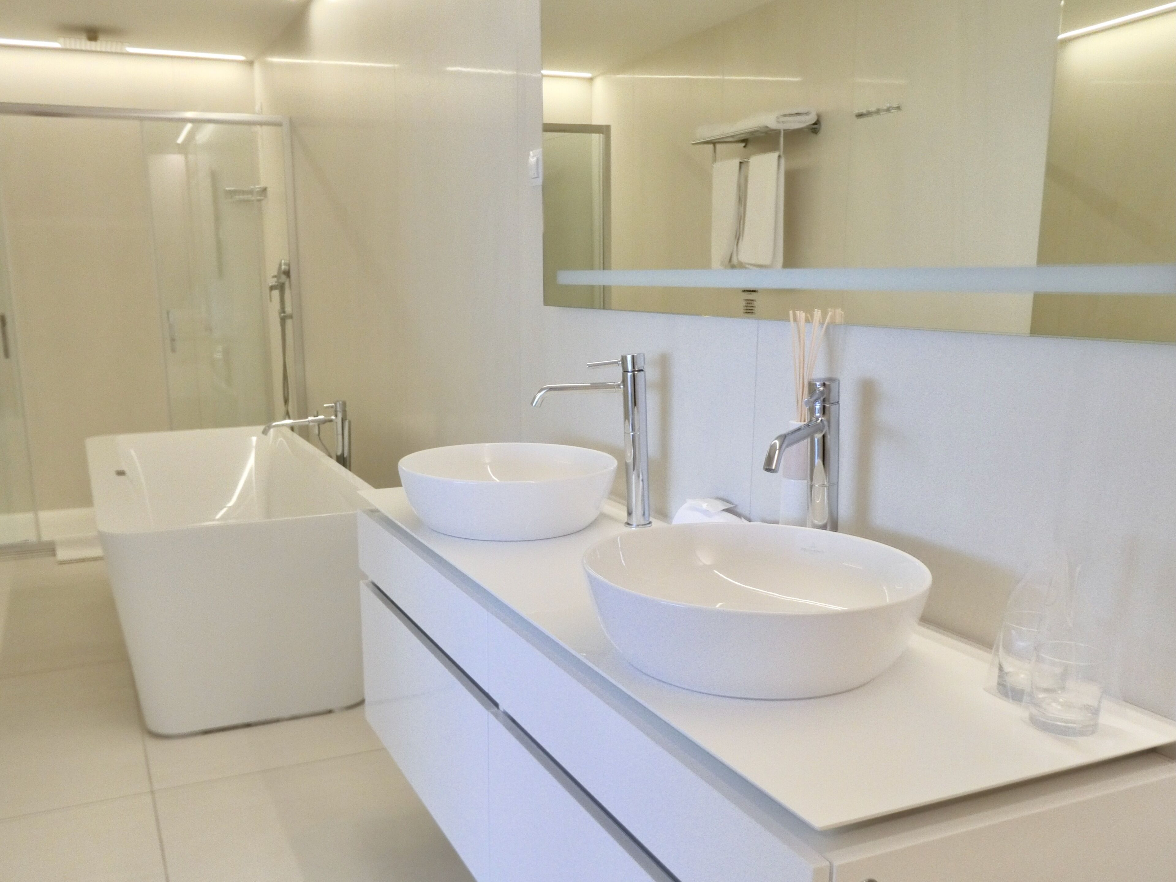 Ein modernes Badezimmer mit zwei weißen Waschbecken, einer großzügigen Badewanne und einer Duschkabine aus Glas.
