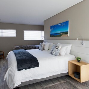 A modern bedroom with a large bed, a nightstand, a wall-mounted light, and a painting of a landscape. - The Hill Boutique Bed & Breakfast (East London)