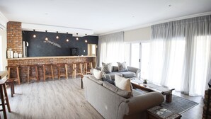 Uma sala de estar moderna com um sofá cinzento, uma mesa de centro e uma parede de tijolos com um espaço para bar.