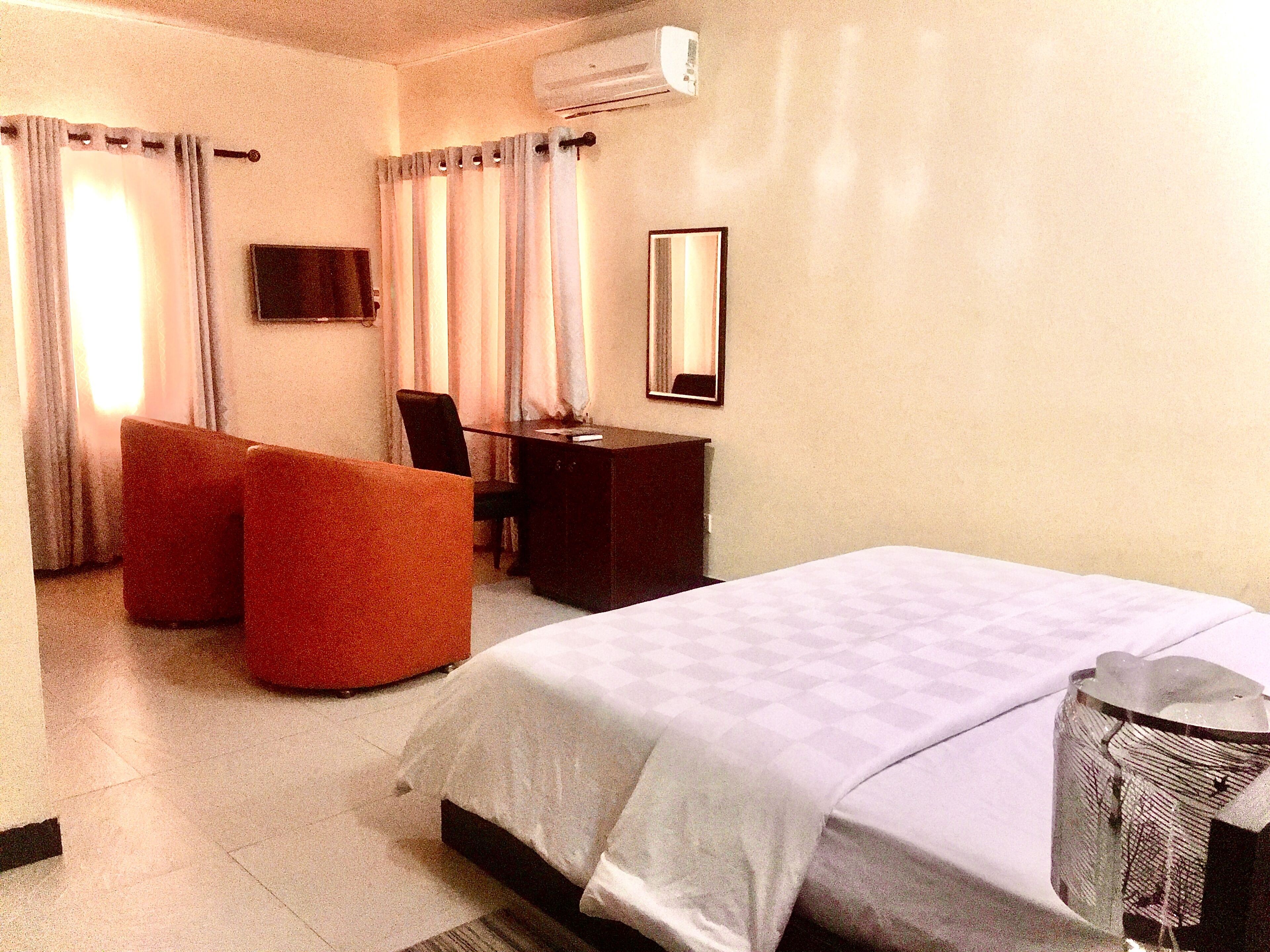 A hotel room with a bed, a desk, a chair, and a sofa.