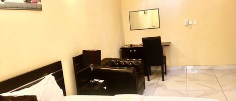 Habitación de hotel con una cama, un escritorio, una silla, una lámpara y un espejo en la pared.
