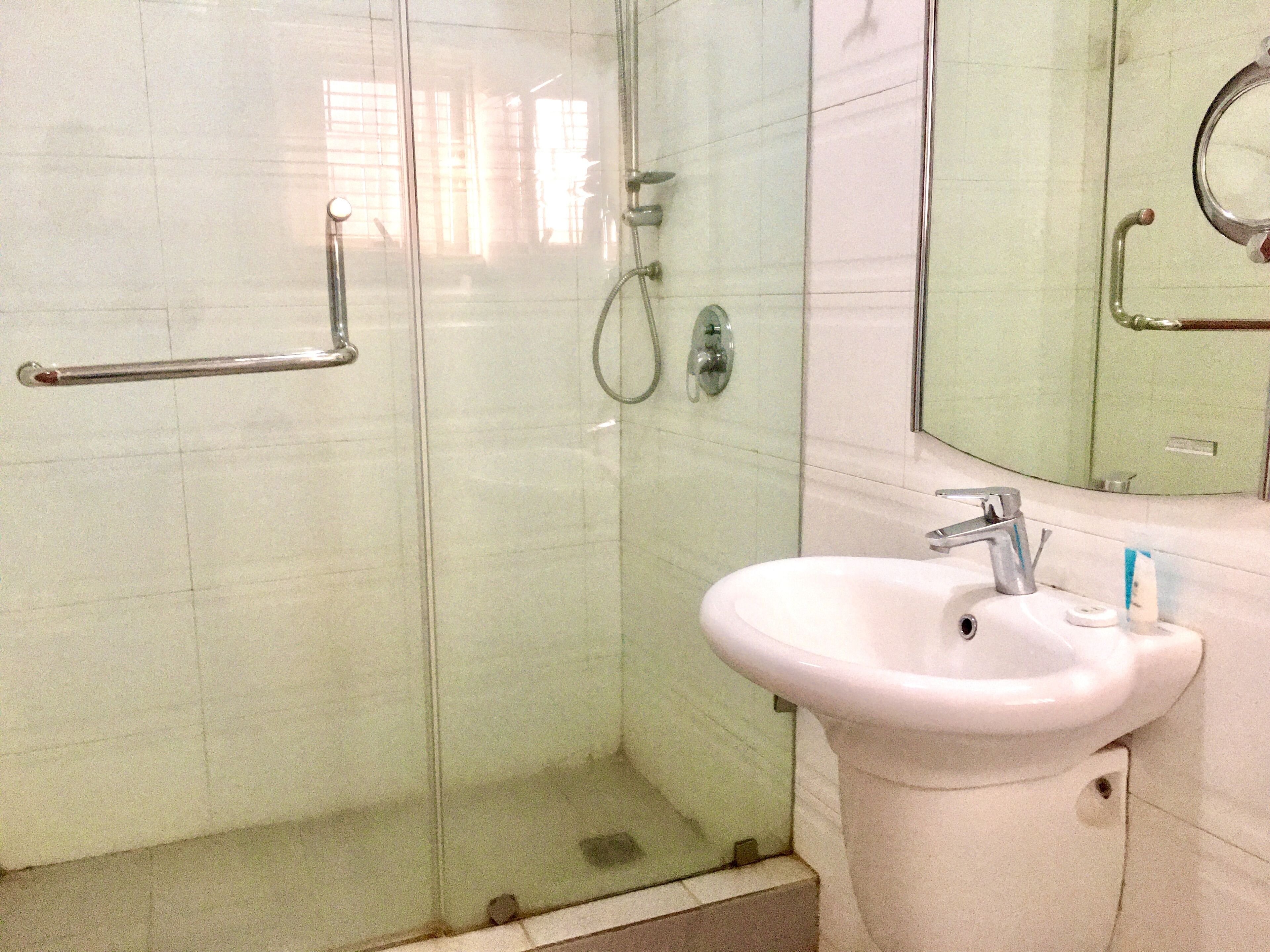 A bathroom with a glass shower enclosure, a white sink, and a mirror.