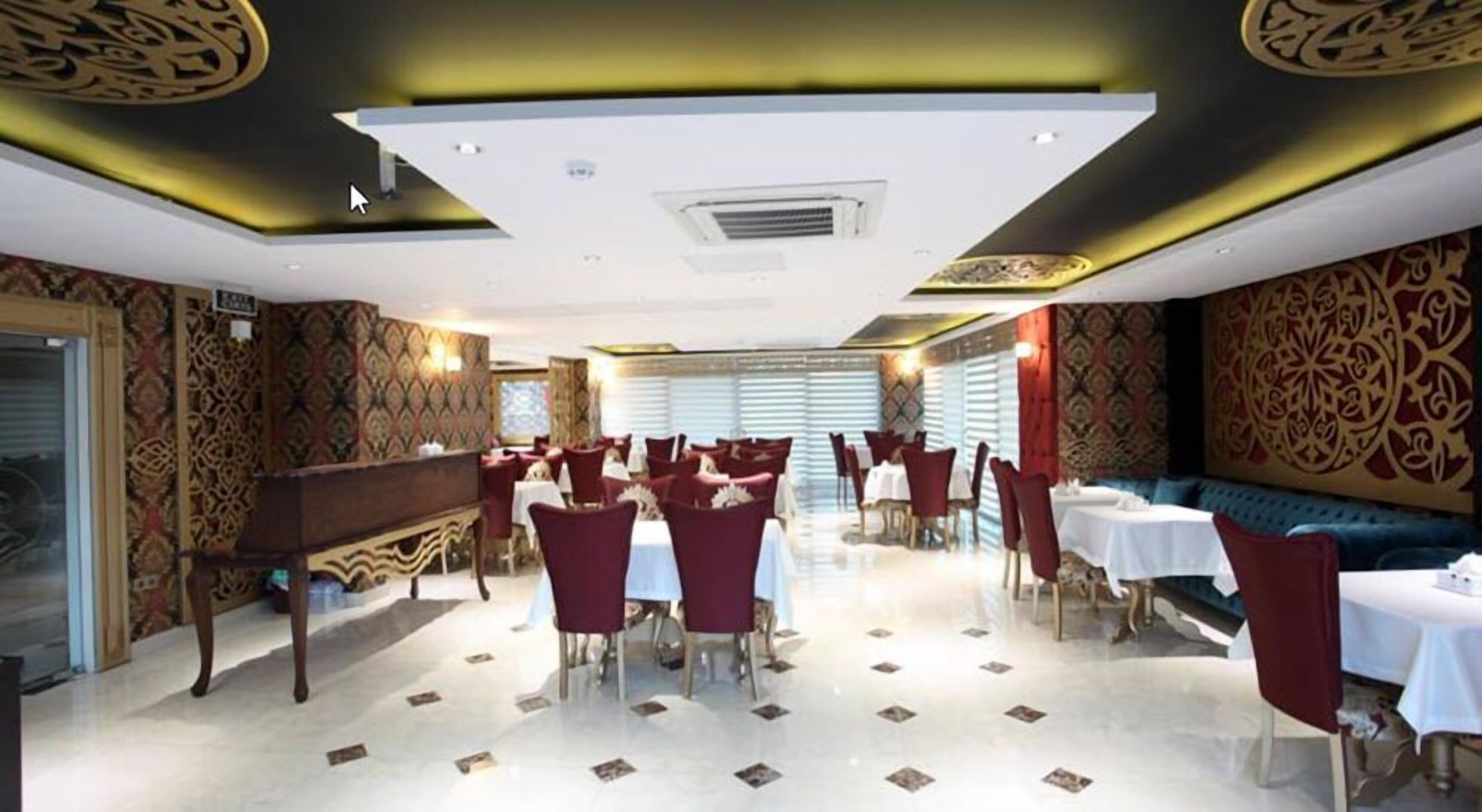 A restaurant with a central bar, multiple tables with red chairs, patterned walls, and a tiled floor.