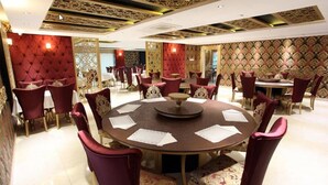 A formal dining room with a round table, red upholstered chairs, and patterned wallpaper. - Tarsus Zorbaz Hotel (Tarsus)