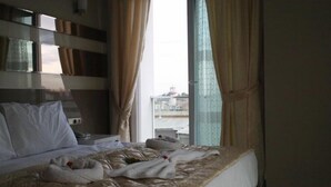 A hotel room with a bed, a bedside table, and a window with curtains. - Tarsus Zorbaz Hotel (Tarsus)