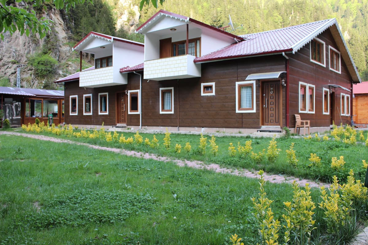 A wooden house with a balcony and a garden with yellow flowers.