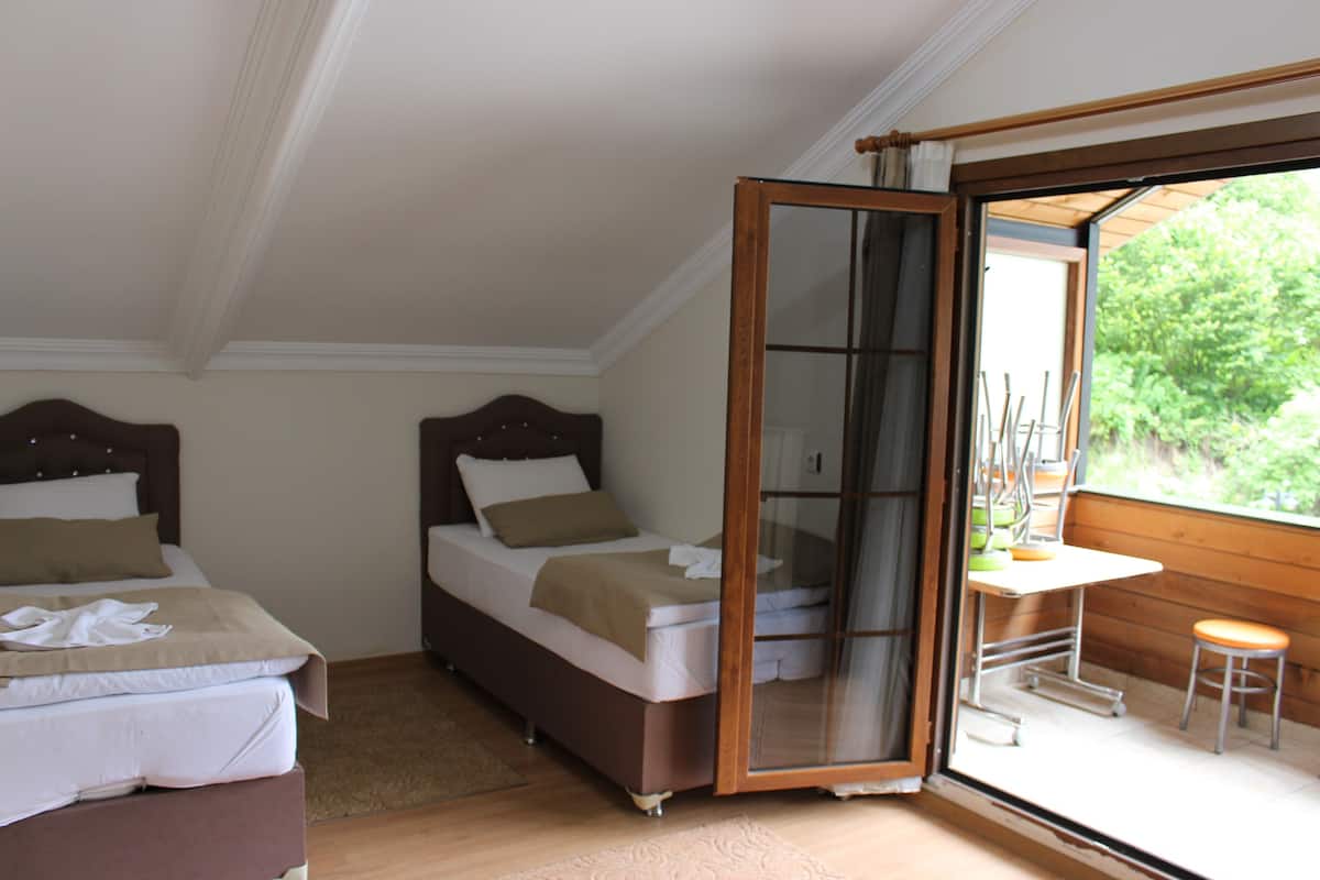 A bedroom with two beds, a wooden-framed sliding door leading to a balcony with a table and chairs.