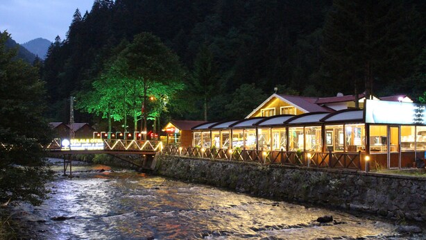 Hotel aan de rivier met een stenen muur en een houten terras met uitzicht op de stromende rivier.