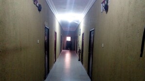 A long, narrow hallway with doors on both sides, leading to a brightly lit room at the end. - Prowess Hotel and Suites (Ota)