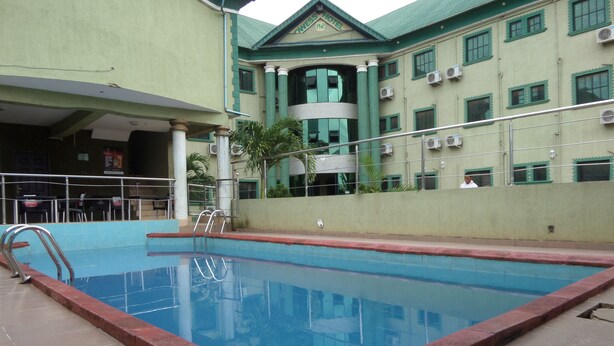 A swimming pool with a red border, surrounded by a building with green columns and a tiled floor. - Prowess Hotel and Suites (Ota)