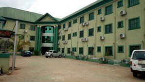 A building with multiple air conditioning units, a car parked in front, and a sign indicating a gym. - Prowess Hotel and Suites (Ota)