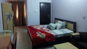 A hotel room with a bed, a desk, a chair, a wardrobe, and a door. - Prowess Hotel and Suites (Ota)