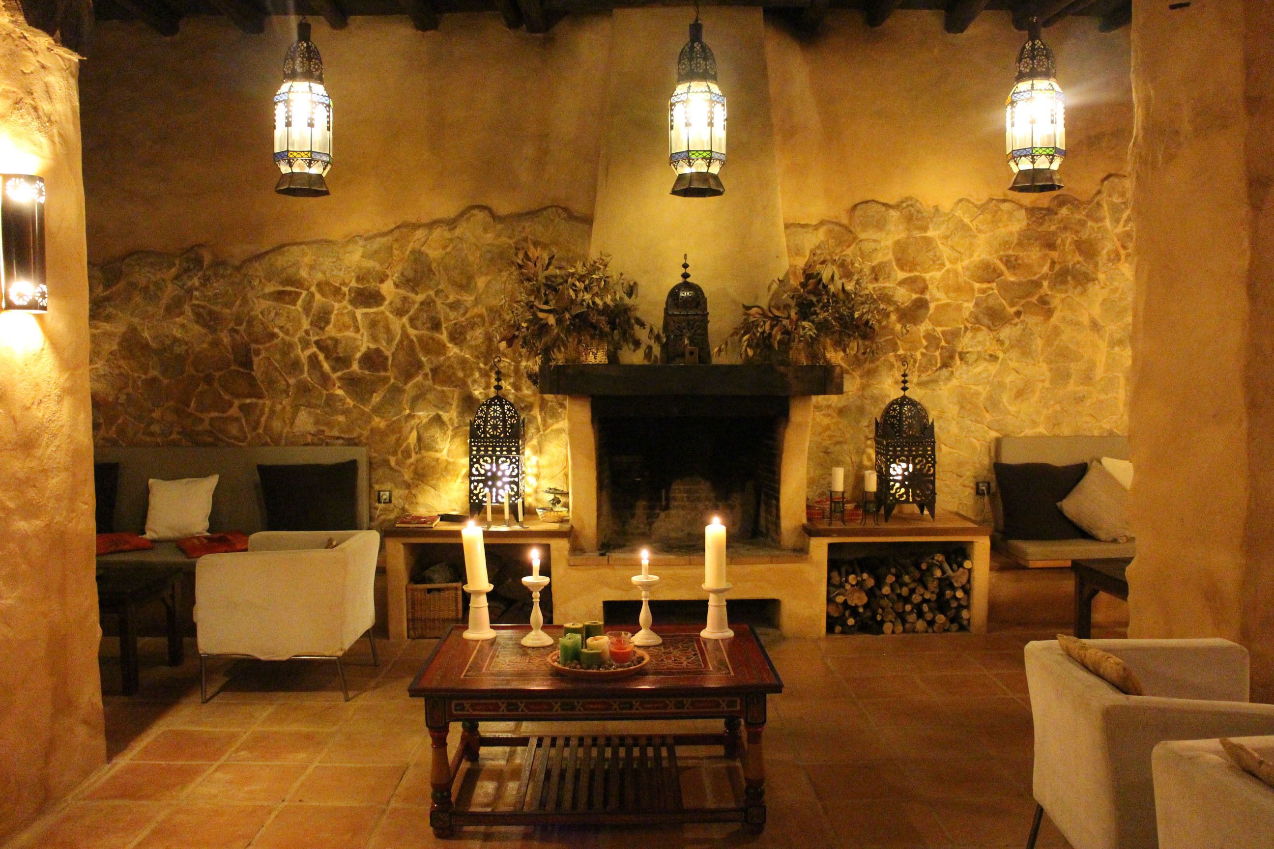 A cozy living room with a stone wall, a fireplace, and three hanging lanterns.