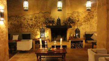 A cozy living room with a stone wall, a fireplace, and three hanging lanterns.