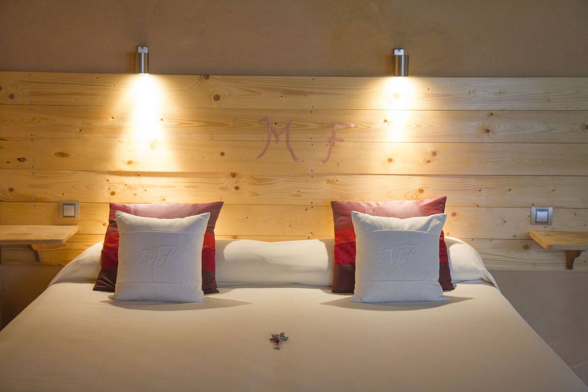 Un lit double avec deux oreillers, une tête de lit en bois et des tables de chevet.