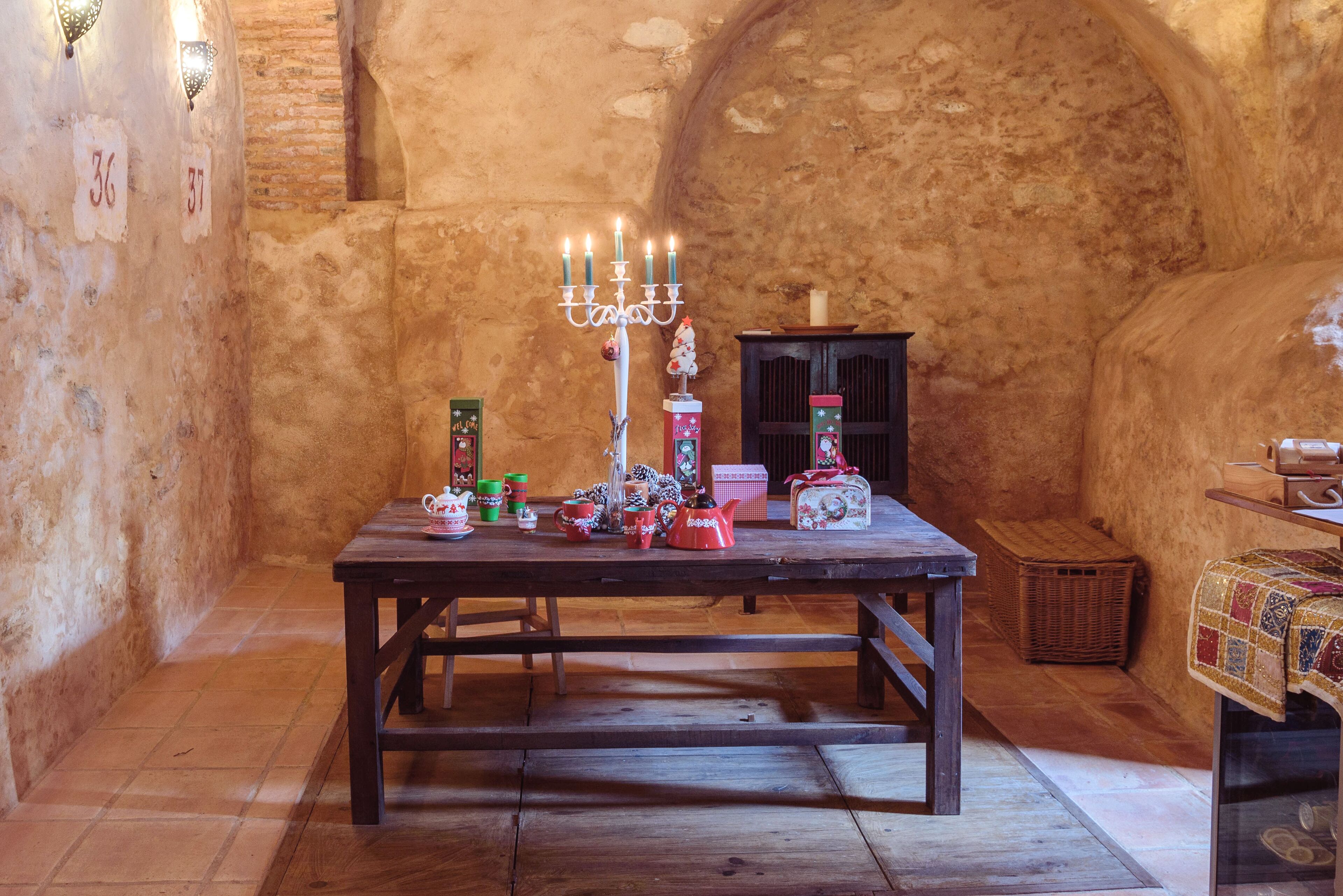 A rustic room with a wooden table, a candelabra, and various decorative items.