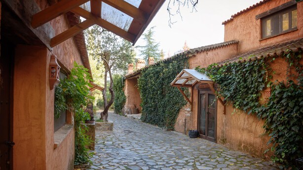 Un sentier pavé de pierres menant à un bâtiment rustique doté d’une porte en bois et d’un petit porche.