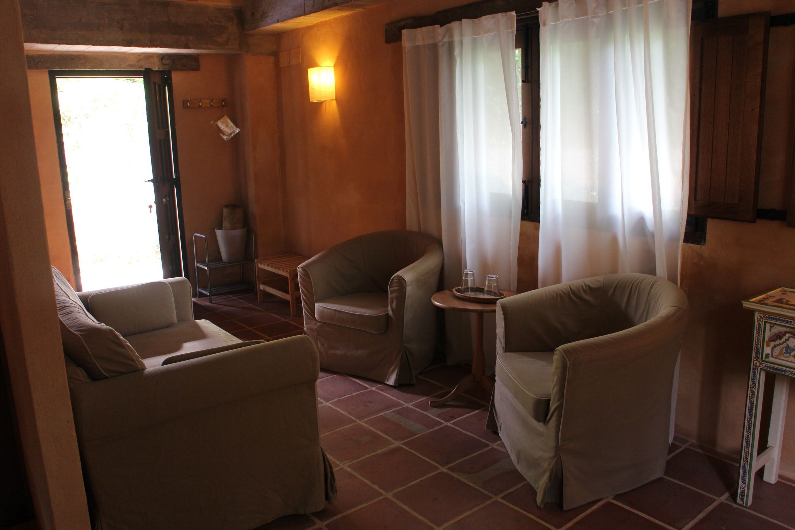 A cozy room with two armchairs, a small table, and a window with sheer curtains.