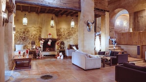 Un intérieur rustique avec des murs en pierre, des poutres en bois, une cheminée et une décoration représentant une tête de taureau.