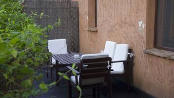 Un patio al aire libre con una mesa de madera y dos sillas blancas con cojines.