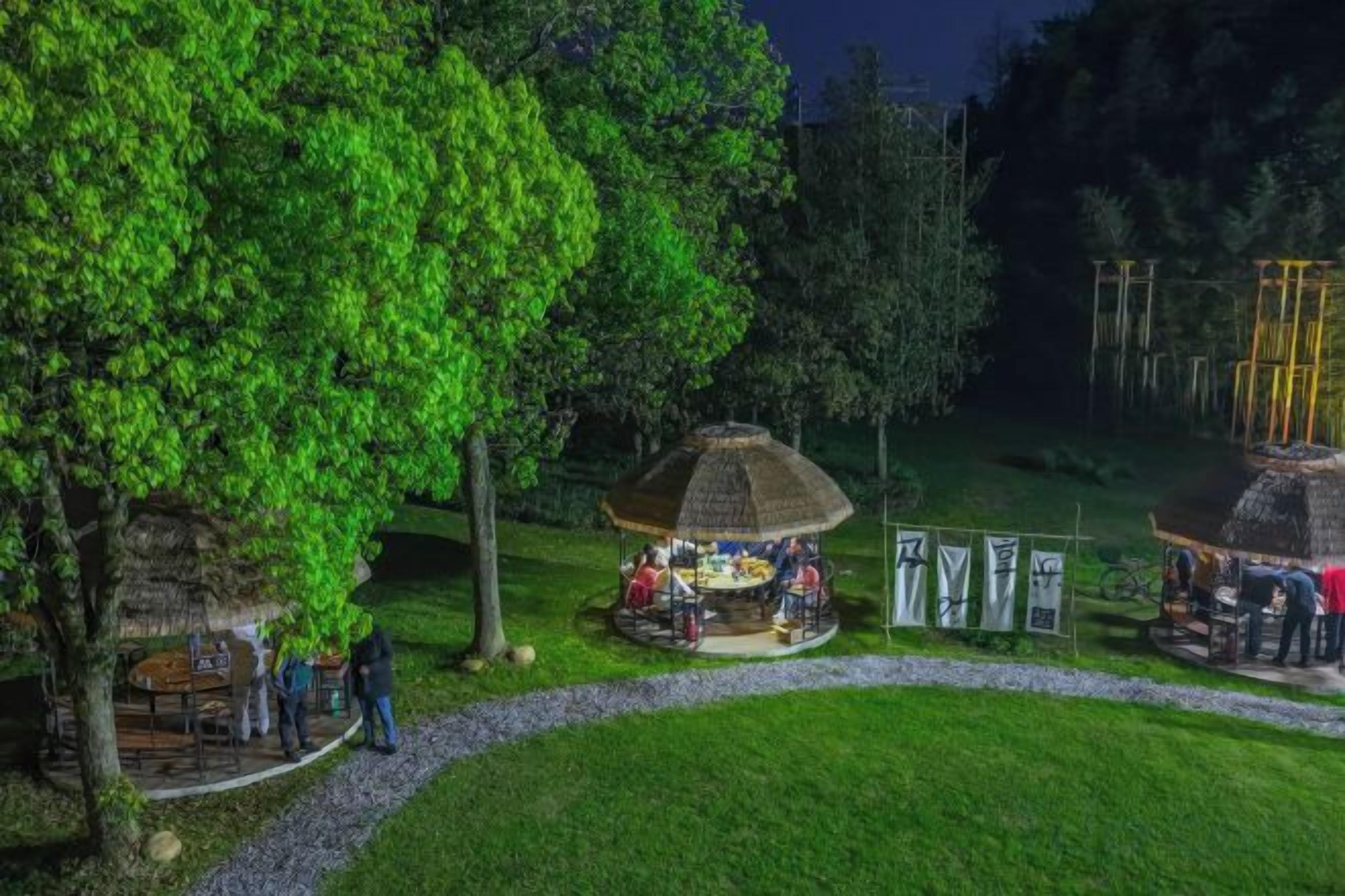 A park with a gazebo, a small hut, and a pathway.