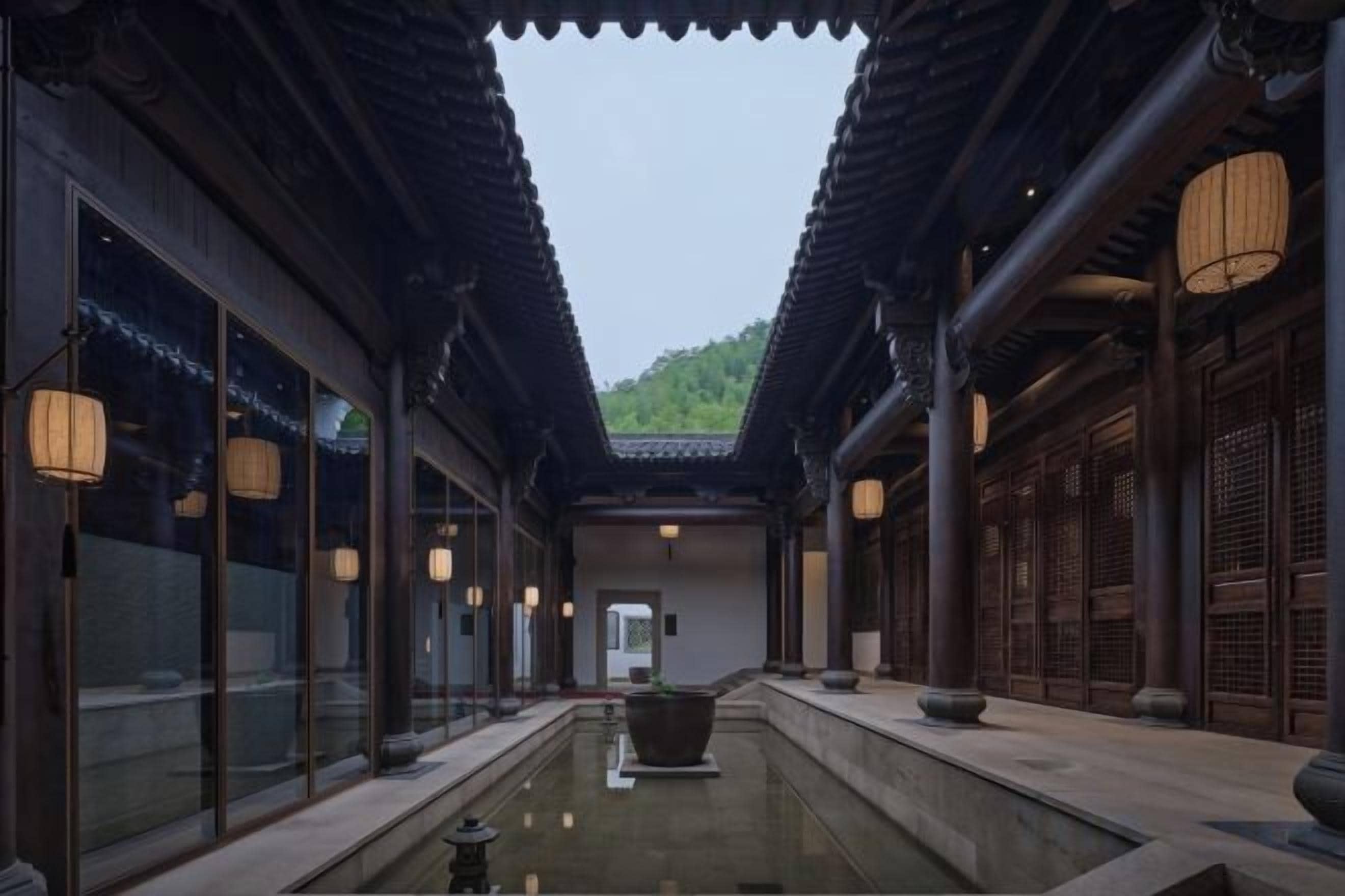 A traditional courtyard with a water feature, wooden architecture, and lanterns.