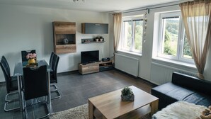 En moderne stue med spiseplads, et fladskærms-tv og en sofa.