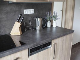 Una cocina moderna con lavavajillas incorporado, hervidor y bloque de cuchillos en la encimera.
