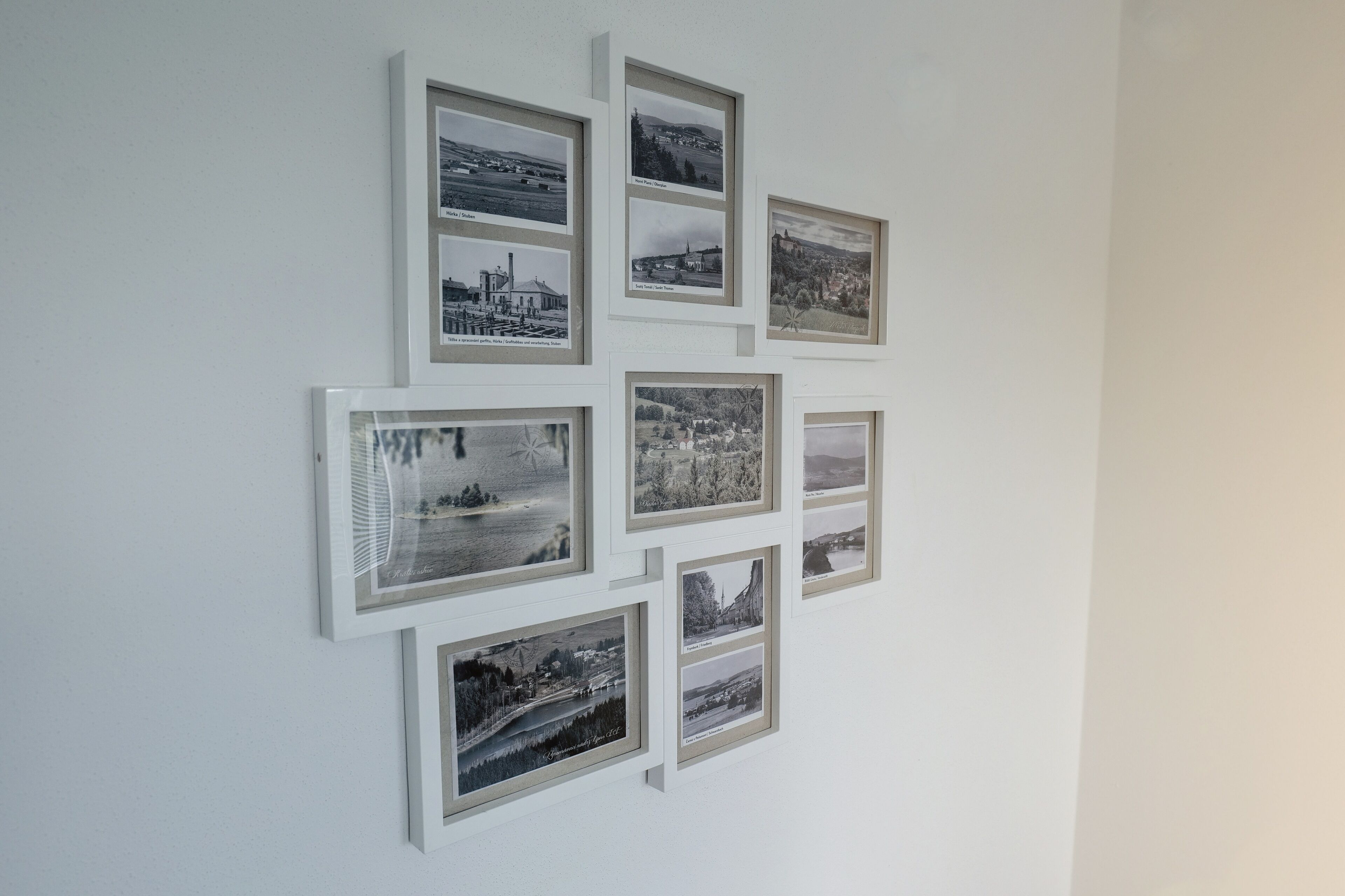 Een muur met meerdere zwart-witfoto's in zwarte lijsten, geordend in een raster.