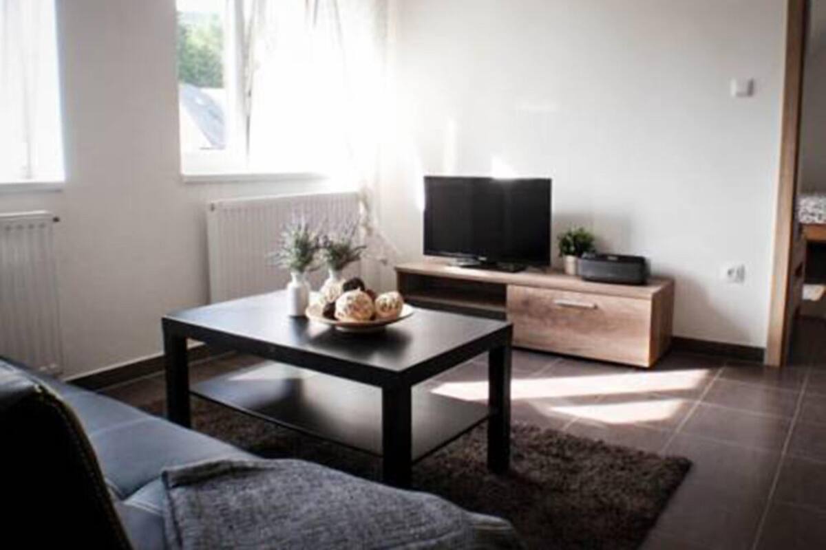 A modern living room with a sofa, a coffee table with decorative items, a television, and a cabinet.