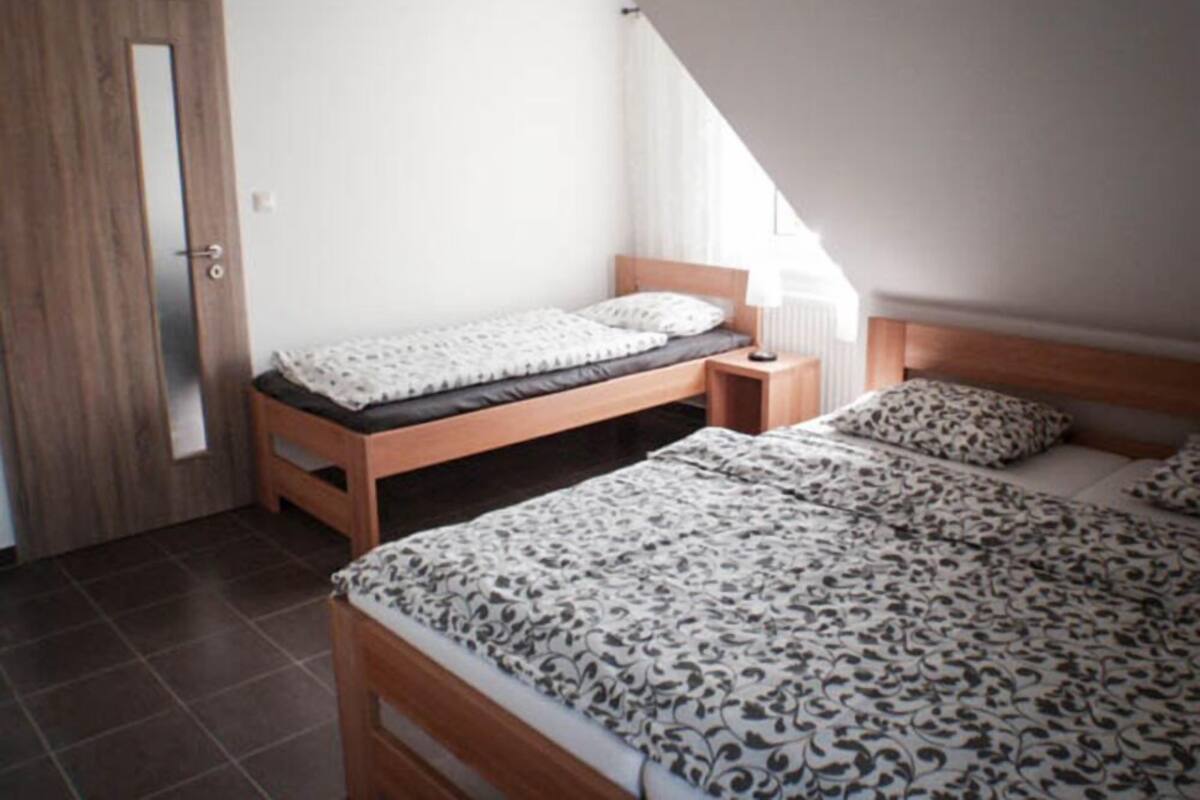 A bedroom with a single bed, a wooden nightstand, a door, and a radiator.