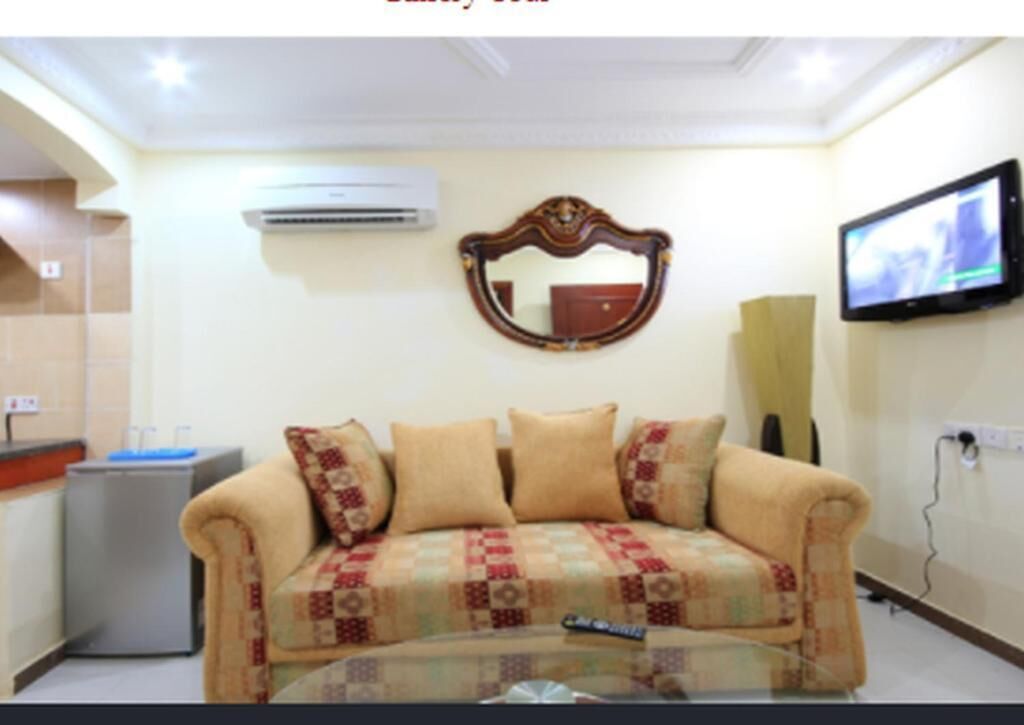 A living room with a sofa, a television, and a wall-mounted mirror.