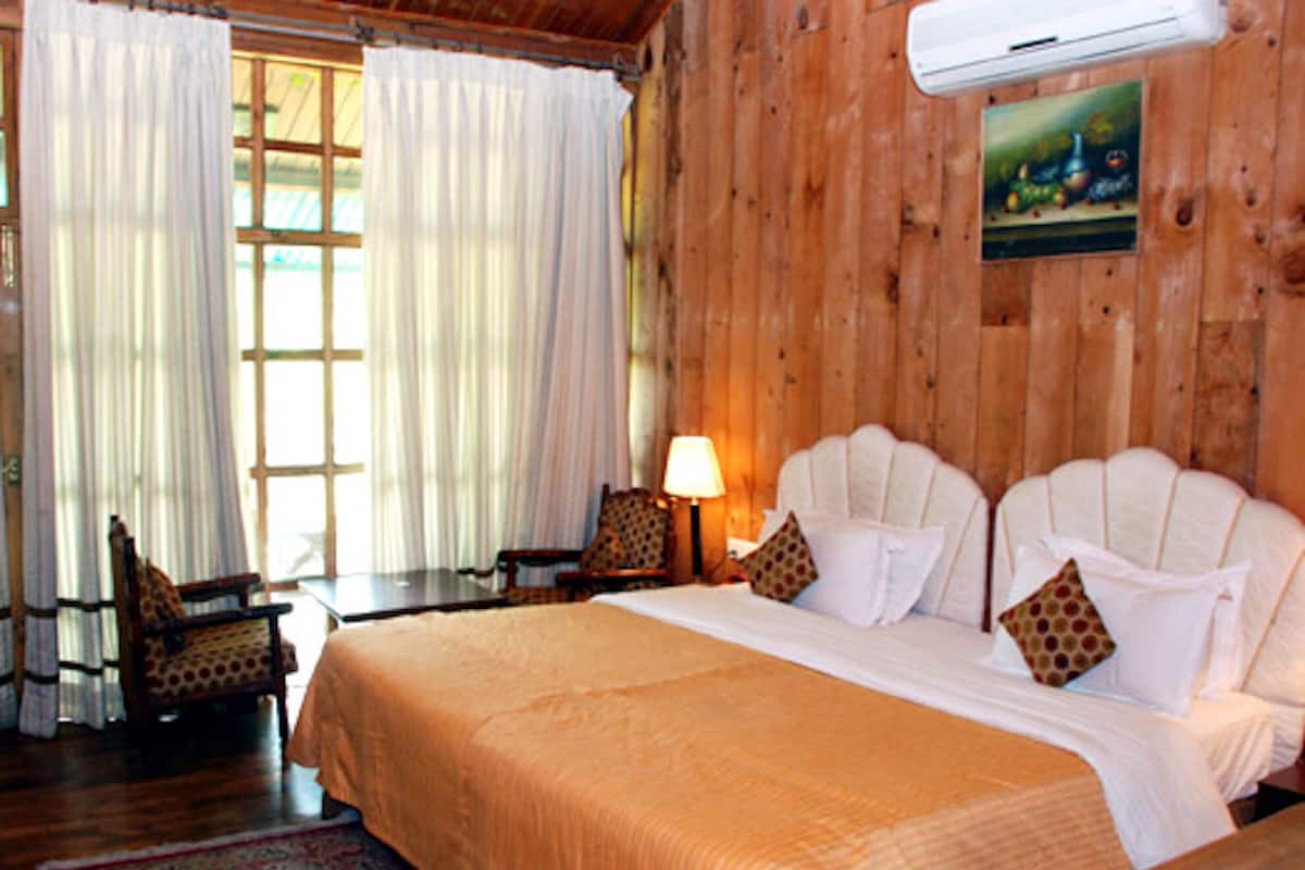 A wooden-paneled room with a bed, a chair, a nightstand, and a lamp.