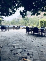 An outdoor seating area with stone flooring and tables and chairs.