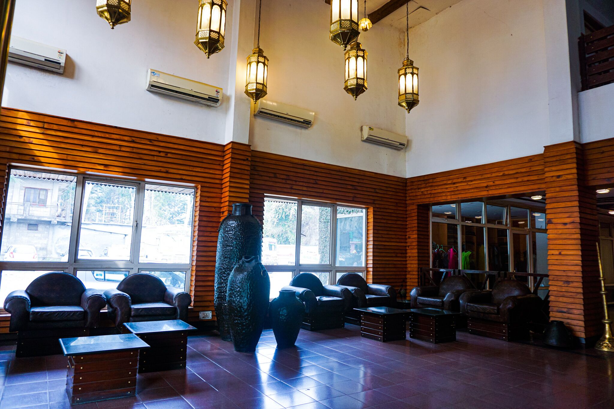 A lobby with leather sofas, a large vase, and hanging lanterns.