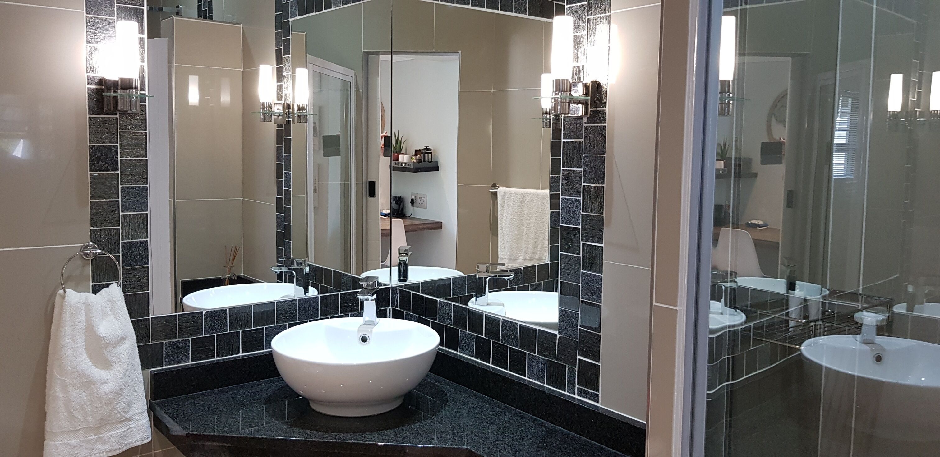 A modern bathroom with two sinks, a large mirror, and a glass shower enclosure.