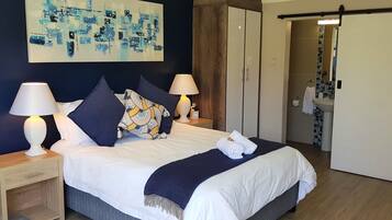 Ein ordentlich bezogenes Bett mit zwei Lampen, einem blauen abstrakten Gemälde und einem Holzschrank in einem Hotelzimmer.