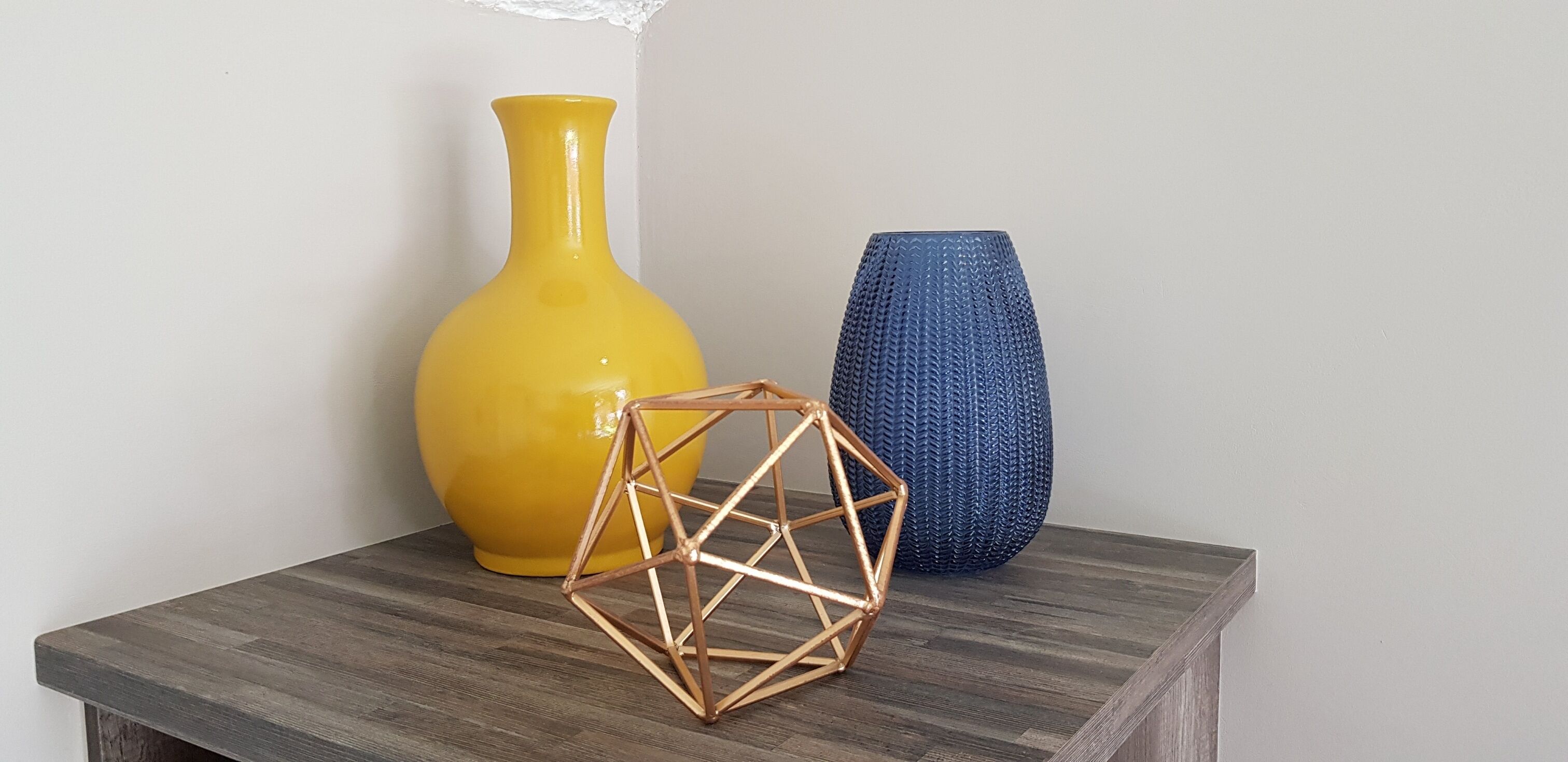 A wooden table with two vases and a geometric sculpture.