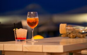 Two cocktails on a table with a blurred background of a sunset and a plane. - Assano Sea Front Luxury (Sithonia)
