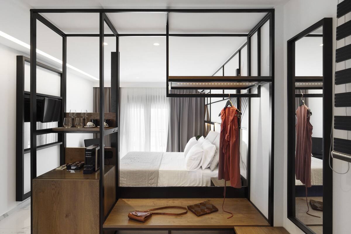 A compact, modern bedroom with a bed, bedside table, and a TV on a shelf.