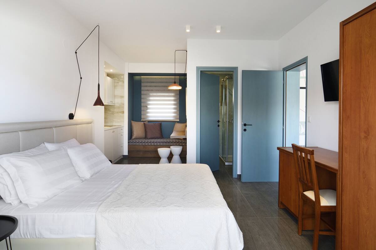 A bedroom with a bed, bedside table, and a wooden desk with a chair.