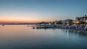 A beachside hotel with sun loungers and umbrellas, a calm sea, and a sunset. - Assano Sea Front Luxury (Sithonia)