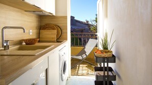 A compact kitchen with a washing machine, a sink, and a small dining area with a chair and a table. - Les Toits de Santa Giulia (Porto-Vecchio)