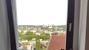 A window with a view of a cityscape, a radiator below, and a bag on the windowsill. - Apartment im Luisenviertel - Grün (Wuppertal)