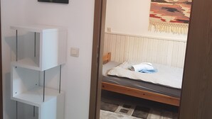 A bedroom with a bed, a white shelving unit, a painting on the wall, and a view of a sunset through a window. - Apartment im Luisenviertel - Grün (Wuppertal)