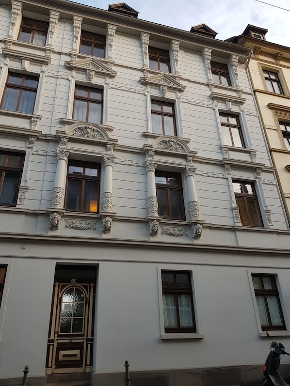 Un immeuble à plusieurs étages doté d’éléments architecturaux classiques, notamment des colonnes richement décorées et des moulures ornementales.