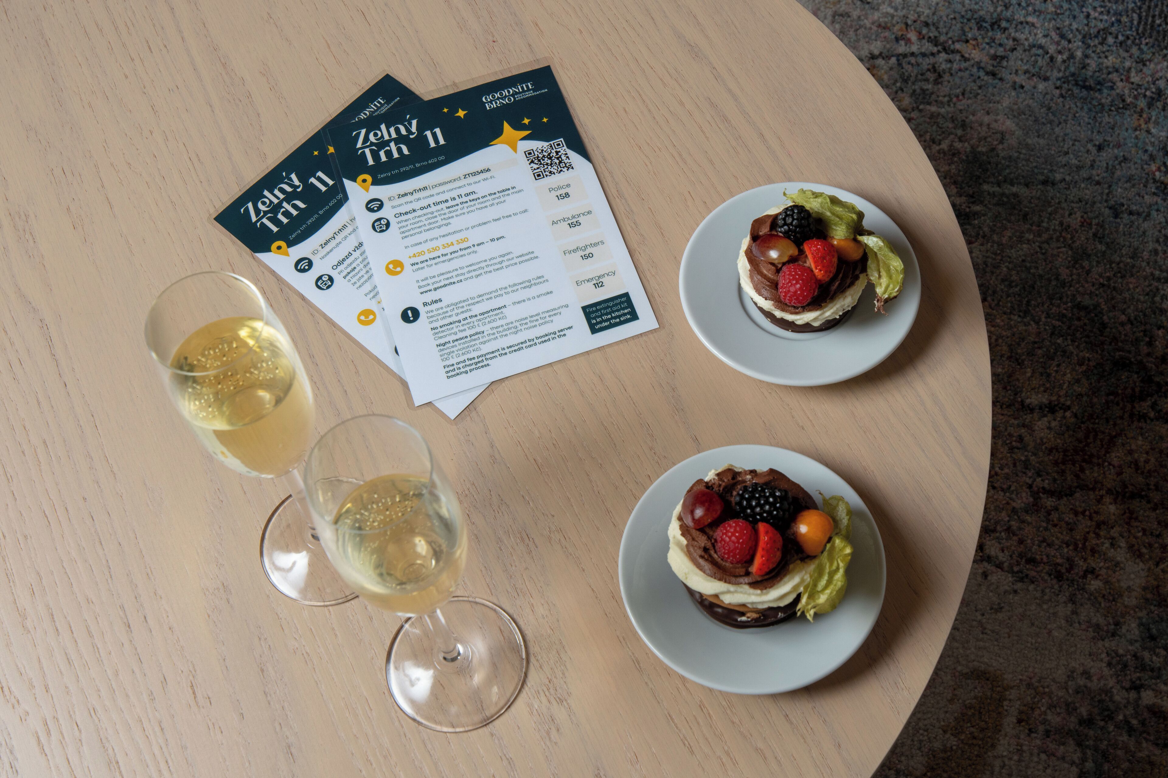 A table with a menu, two glasses of white wine, and two plates of dessert.
