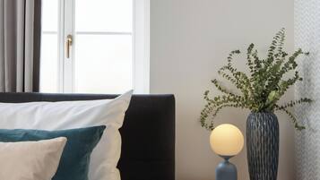 Relax in a stylish room with a comfortable bed, armchair, and potted plant, offering a view of the outside.